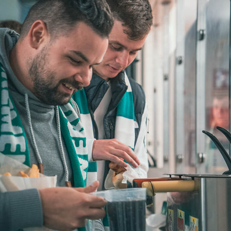 Personen im Stadion mit Getränken und Stadionwurst
