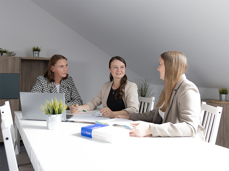 Drei Personen arbeiten an einem Tisch